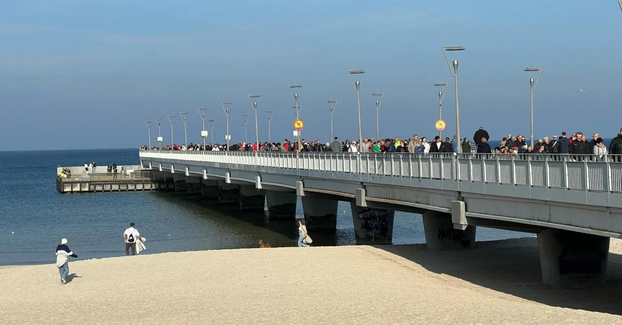 Tłum ludzi spaceruje po molo w Kołobrzegu. Czy molo w Kołobrzegu jest płatne? Na razie wygląda na to, że nie ma żadnych bramek.