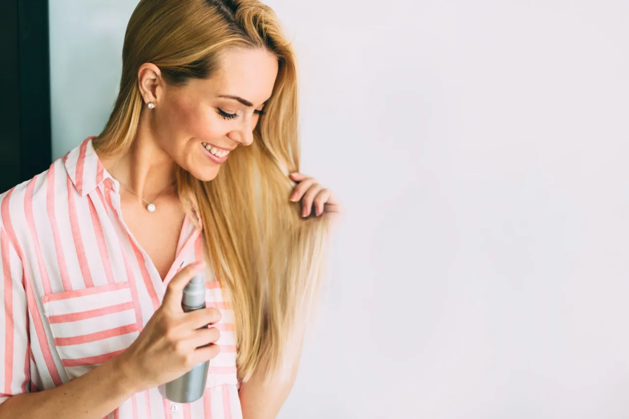 Kobieta aplikująca lakier do włosów, mgiełka