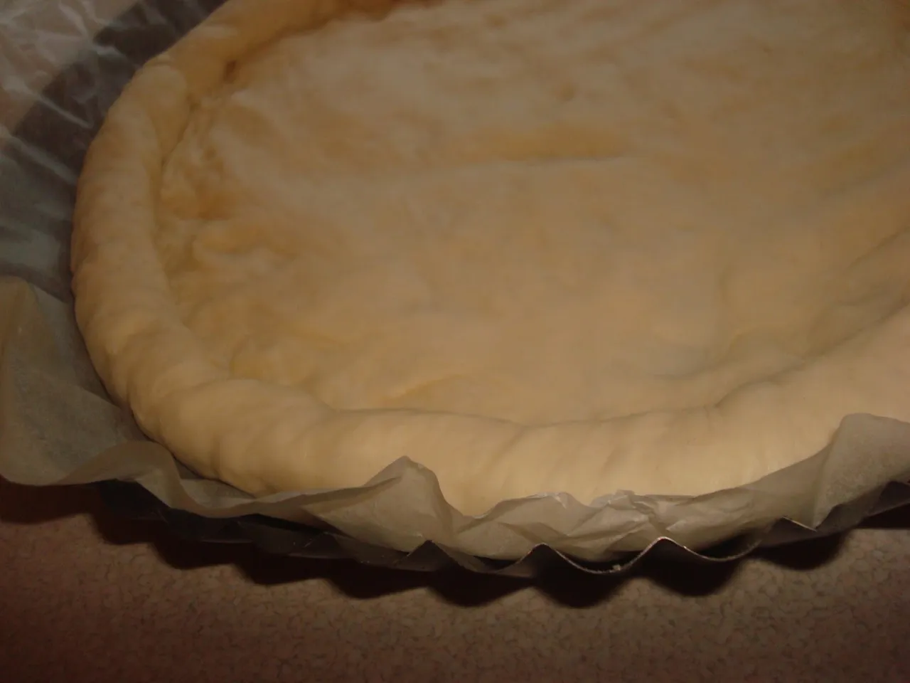 Surowe ciasto na pizzę, z puszystymi brzegami, gotowe do pieczenia. Wygląda jak pizza jak z Pizza Hut!