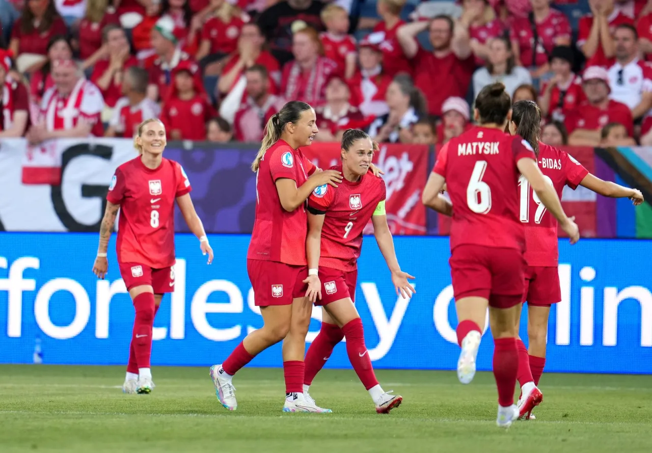 Piłkarki w czerwonych strojach świętują bramkę. Widać dumę i radość, jak wiele reprezentacji w piłce nożnej może osiągnąć dzięki determinacji.