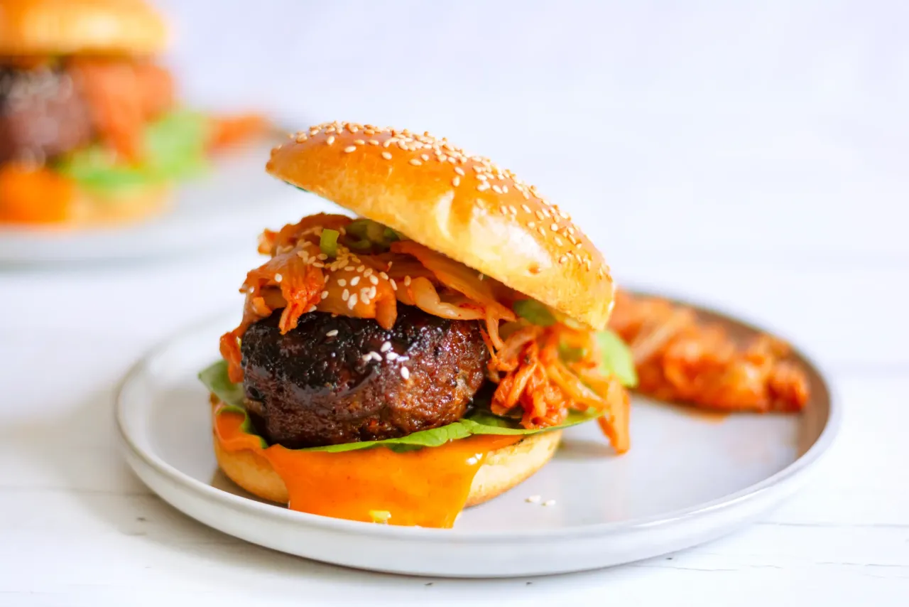 Pikantny burger z wołowiny z chrupiącym kimchi i sosem. Idealny pomysł na to, z czym podawać kimchi, gdy masz ochotę na coś nowego.