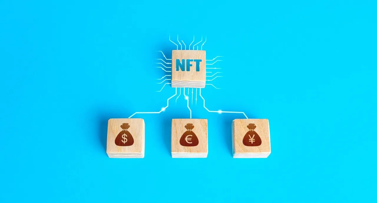 Drewniane klocki z symbolami walut (dolar, euro, jen) połączone z klockiem NFT. Wizualizacja strategii jak wyplacic kryptowaluty bez podatku.