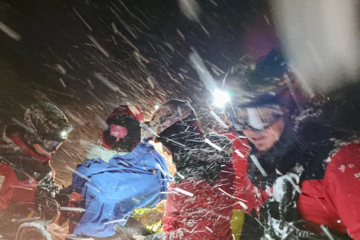 Ratownik g&oacute;rski pomaga turyście w burzy przed schroniskiem