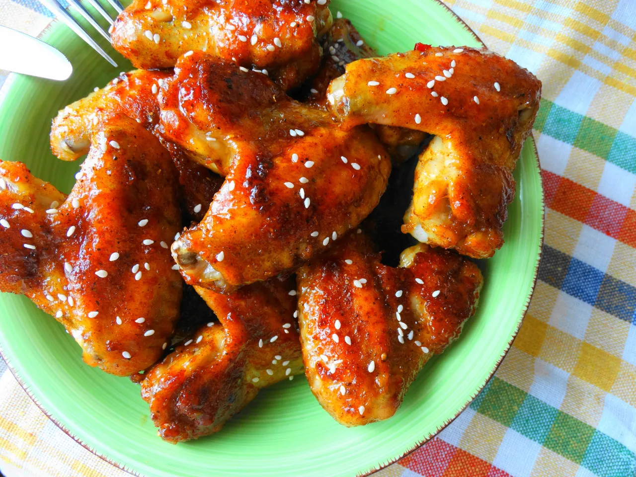 Skrzydełka w miodzie i sosie sojowym, posypane sezamem, na zielonym talerzu. Kwestia smaku, kt&oacute;rą warto poznać!