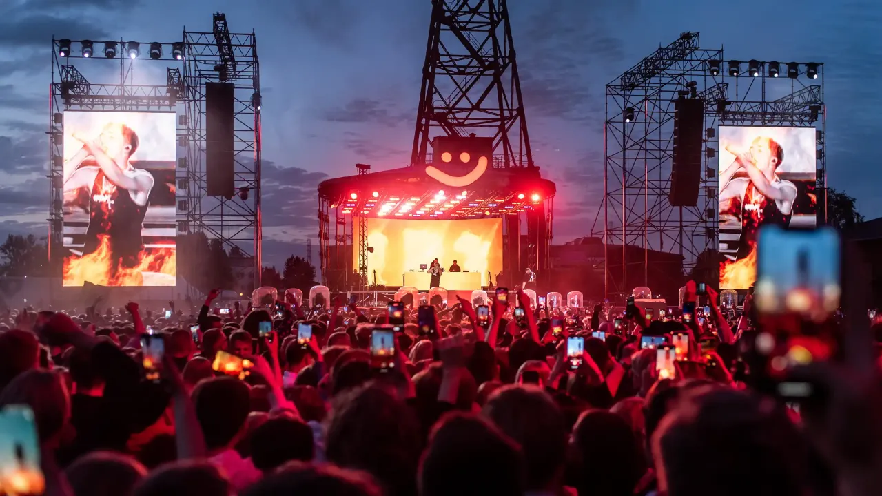 Tłum ludzi na koncercie rapera Maty, wszyscy nagrywają telefonami. W tle scena z wielkimi ekranami, na kt&oacute;rych widać artystę. Koncert trwa, a atmosfera jest gorąca.