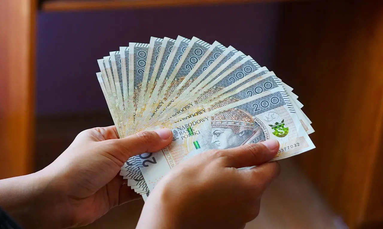 Dwie ręce trzymają wachlarz banknot&oacute;w 200 zł. Zastanawiasz się, co jeśli nie stać mnie na wymianę pieca?