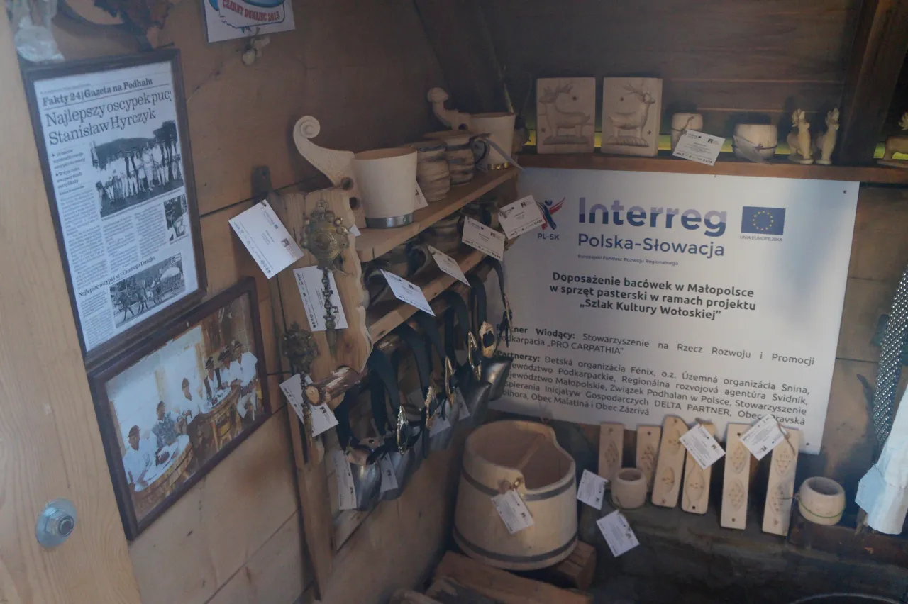 Bac&oacute;wka z tradycyjnymi towarami: oscypek, dzwonki pasterskie, drewniane formy do sera.