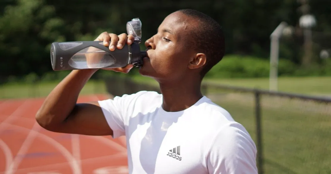Biegacz pije wodę przed treningiem