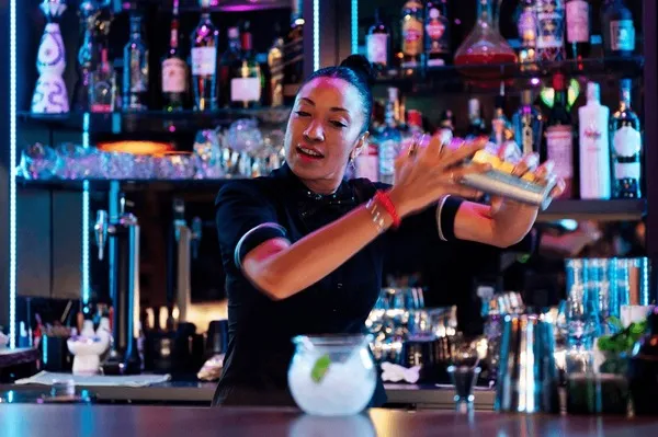 Barman przygotowujący koktajl z uśmiechem