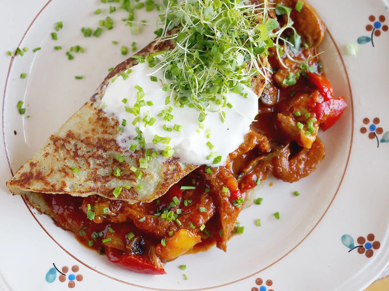 Placki po zbójnicku: złocisty placek ziemniaczany z gulaszem, śmietaną i kiełkami. Pyszne danie, które rozgrzeje każdego!