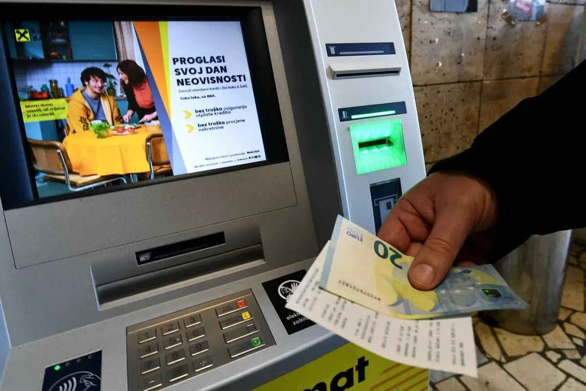 Ręka trzyma banknot 20 euro i paragon przy bankomacie. W Grecji, podobnie jak w wielu krajach UE, obowiązuje euro.