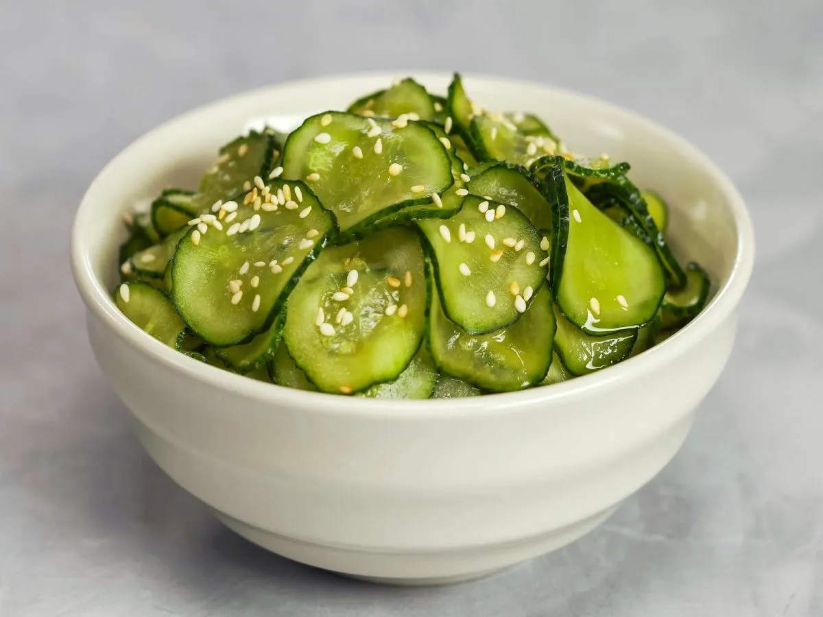 Chrupiące og&oacute;rki po japońsku, posypane sezamem, w białej miseczce.