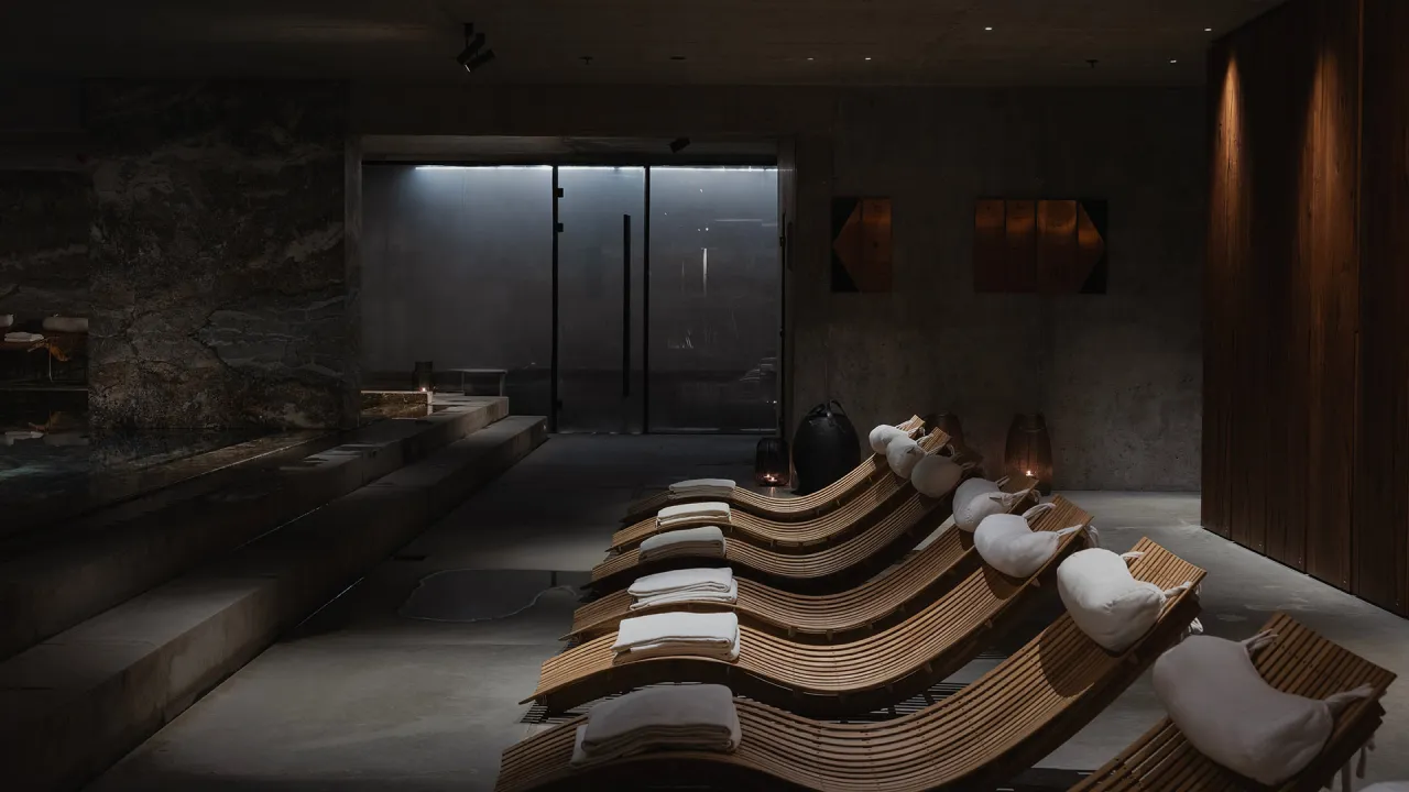 Relaks w nowoczesnym spa niedaleko Warszawy. Drewniane leżaki z poduszkami i ręcznikami czekają na gości.