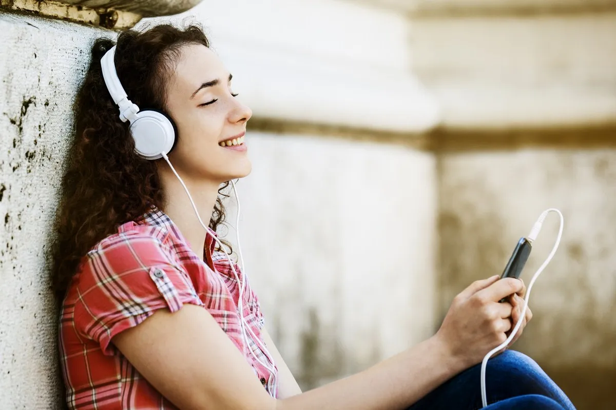 Osoba słuchająca muzyki zamyślona, słuchawki, refleksja