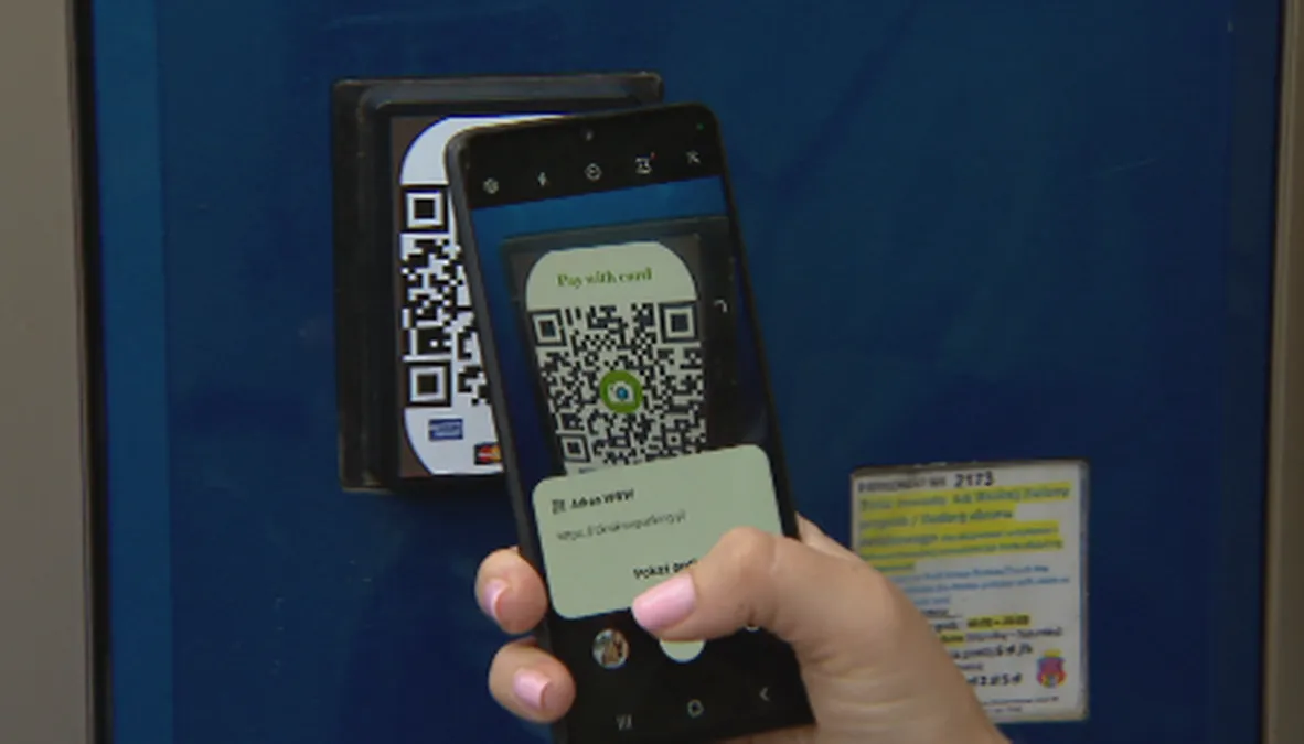 osoba skanująca telefonem kod QR na plakacie w mieście