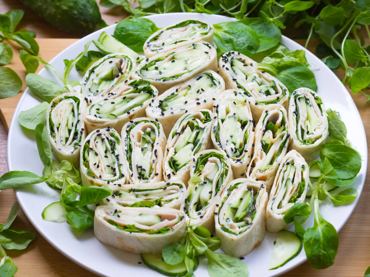 Roladki z tortilli z ogórkiem i ziołami, posypane czarnym sezamem. Idealne, gdy zastanawiasz się, jak zawijać tortille na przekąski.