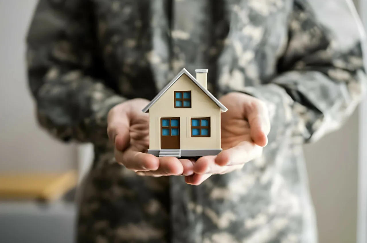 Żołnierz w mundurze trzyma w dłoniach model domu. Czy wojsko daje mieszkanie? To pytanie nurtuje wielu.