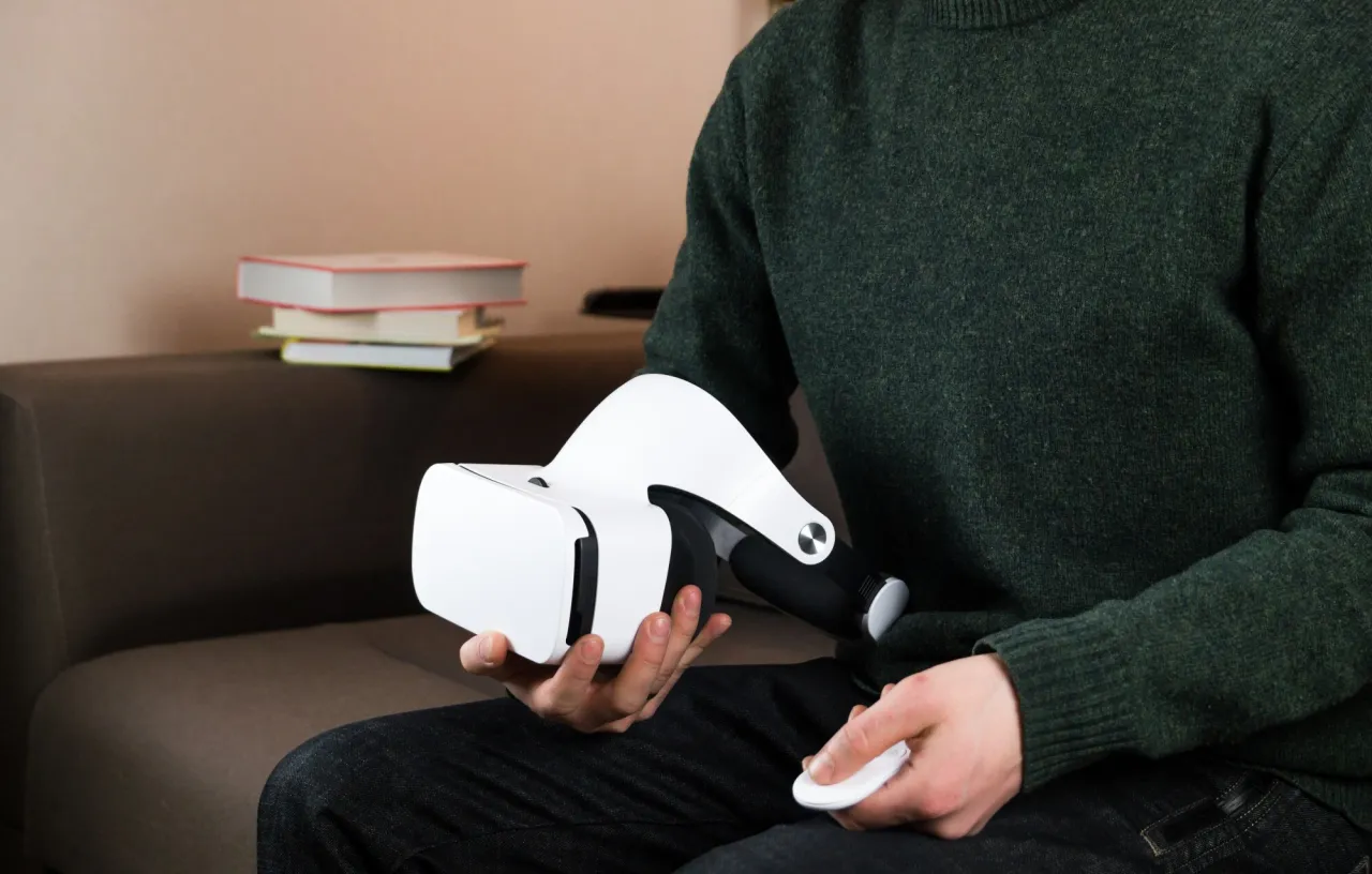 Mężczyzna trzyma białe okulary VR i kontroler, gotowy do podłączenia okular&oacute;w VR do PS4.