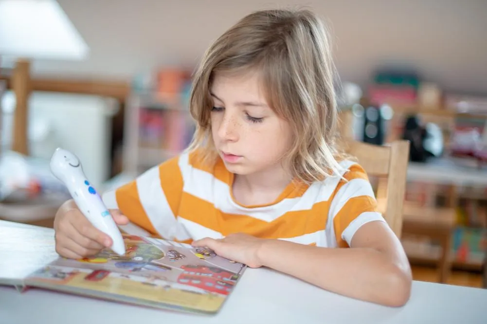 dziecko czyta interaktywną książkę z m&oacute;wiącym pi&oacute;rem