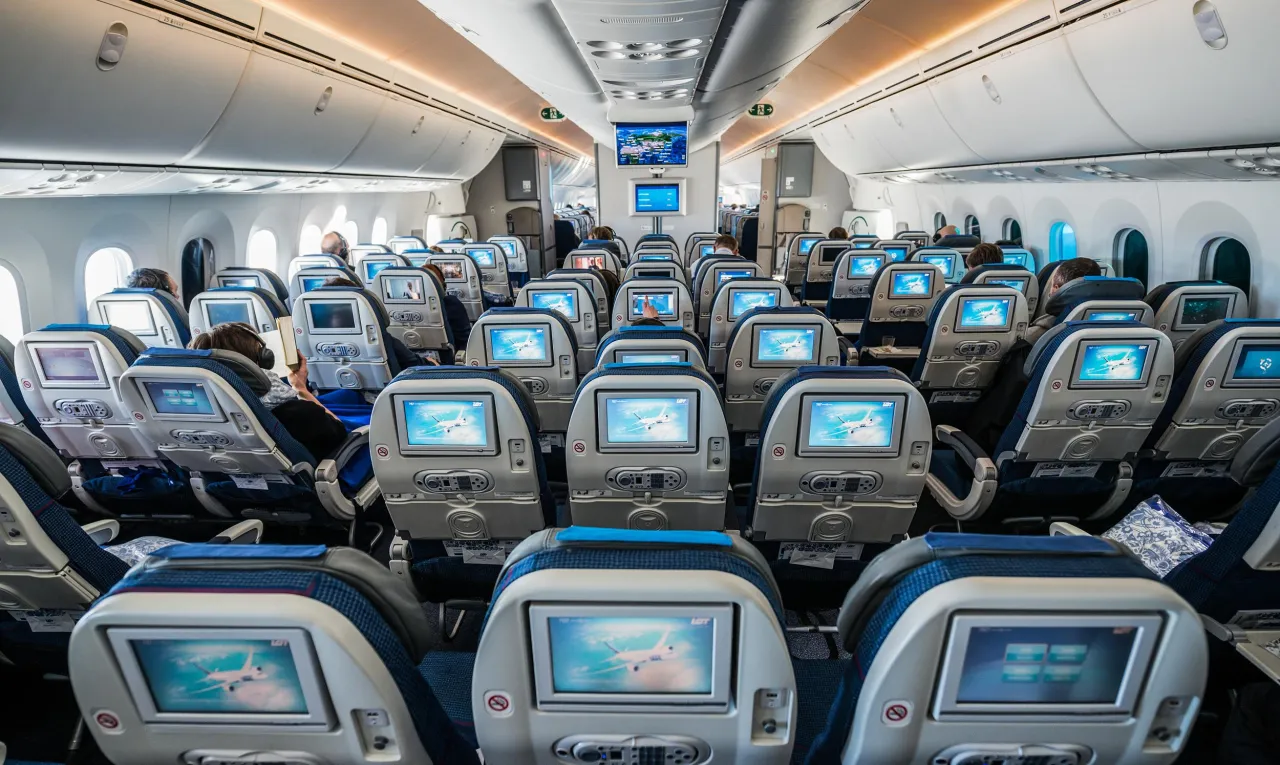 Wnętrze Dreamlinera LOT-u. Pasażerowie siedzą w rzędach, każdy z własnym ekranem. Czas lotu do Tajlandii może być długi, ale rozrywka na pokładzie umili podróż.