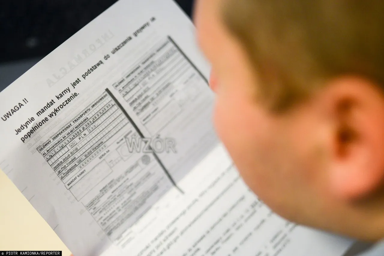 Osoba czyta dokument, kt&oacute;ry pokazuje, jak wygląda mandat z fotoradaru. Widać nagł&oacute;wek 