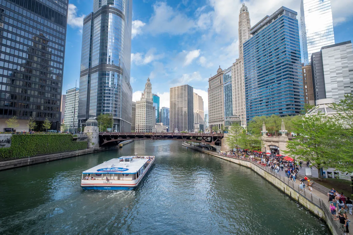 Rejs po rzece w Chicago, gdzie leży to miasto, z widokiem na drapacze chmur i turyst&oacute;w spacerujących brzegiem.