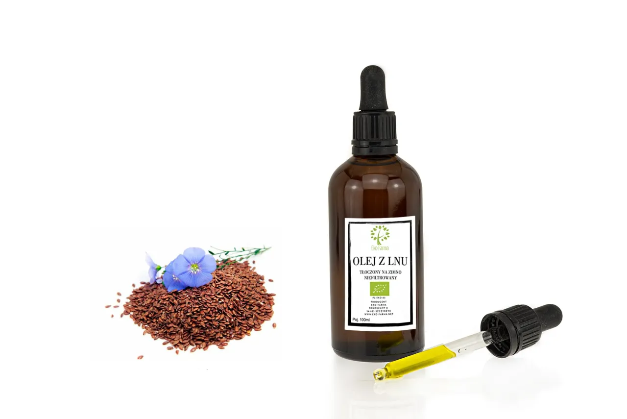 Olej lniany w butelce na tle ziaren lnu i świeżych owoców