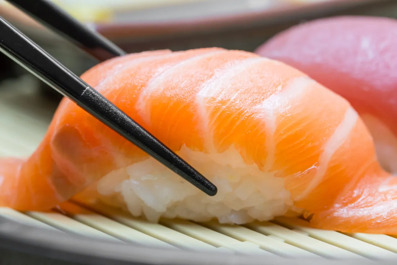 Jak trzymać pałeczki do sushi? Delikatnie chwyć kawałek łososia na ryżu.