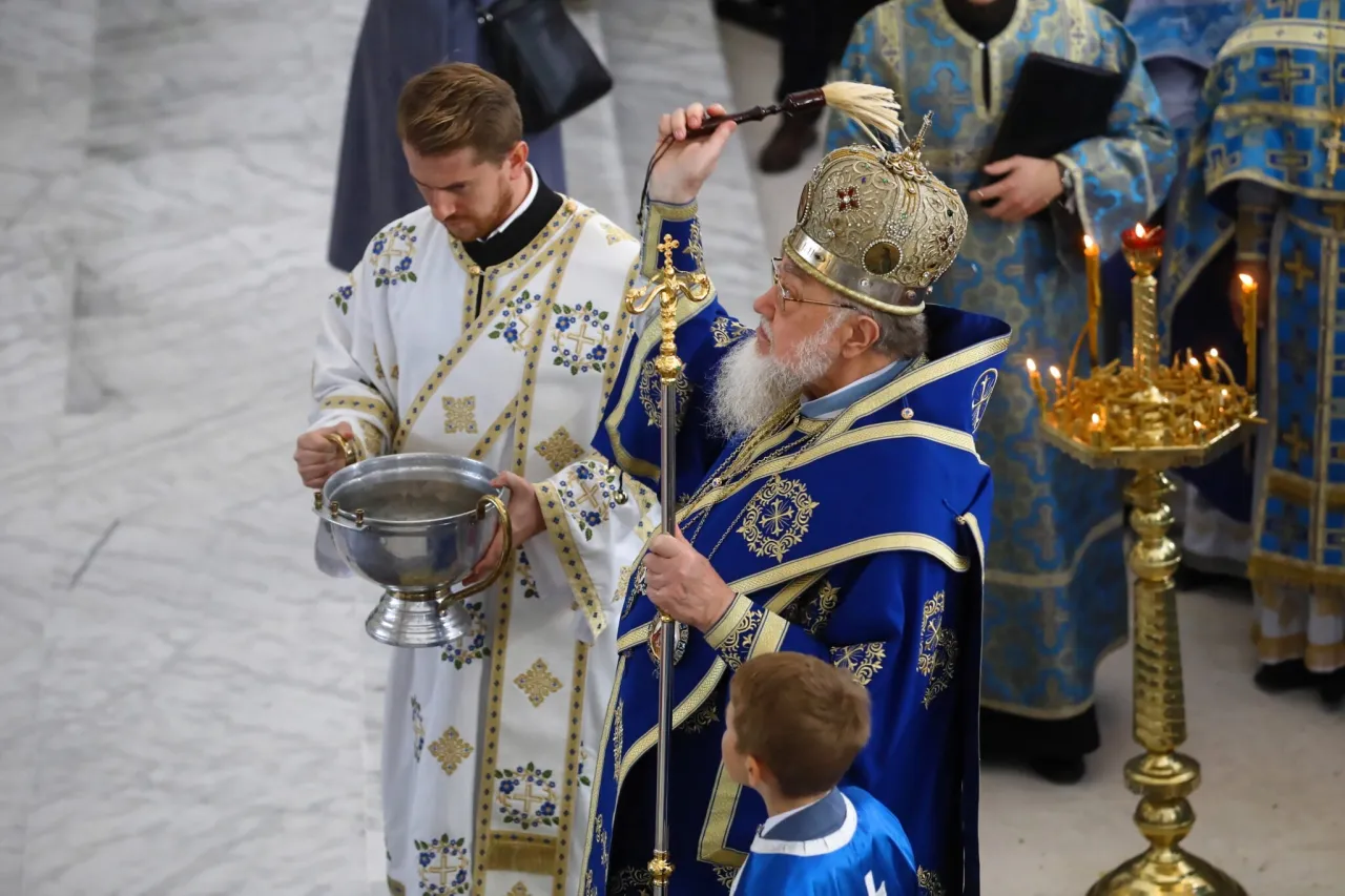 Biskup w bogatych szatach, z koroną na głowie, błogosławi wodę podczas ceremonii. To ważny moment tytułu biskupów w liturgii greckiej.