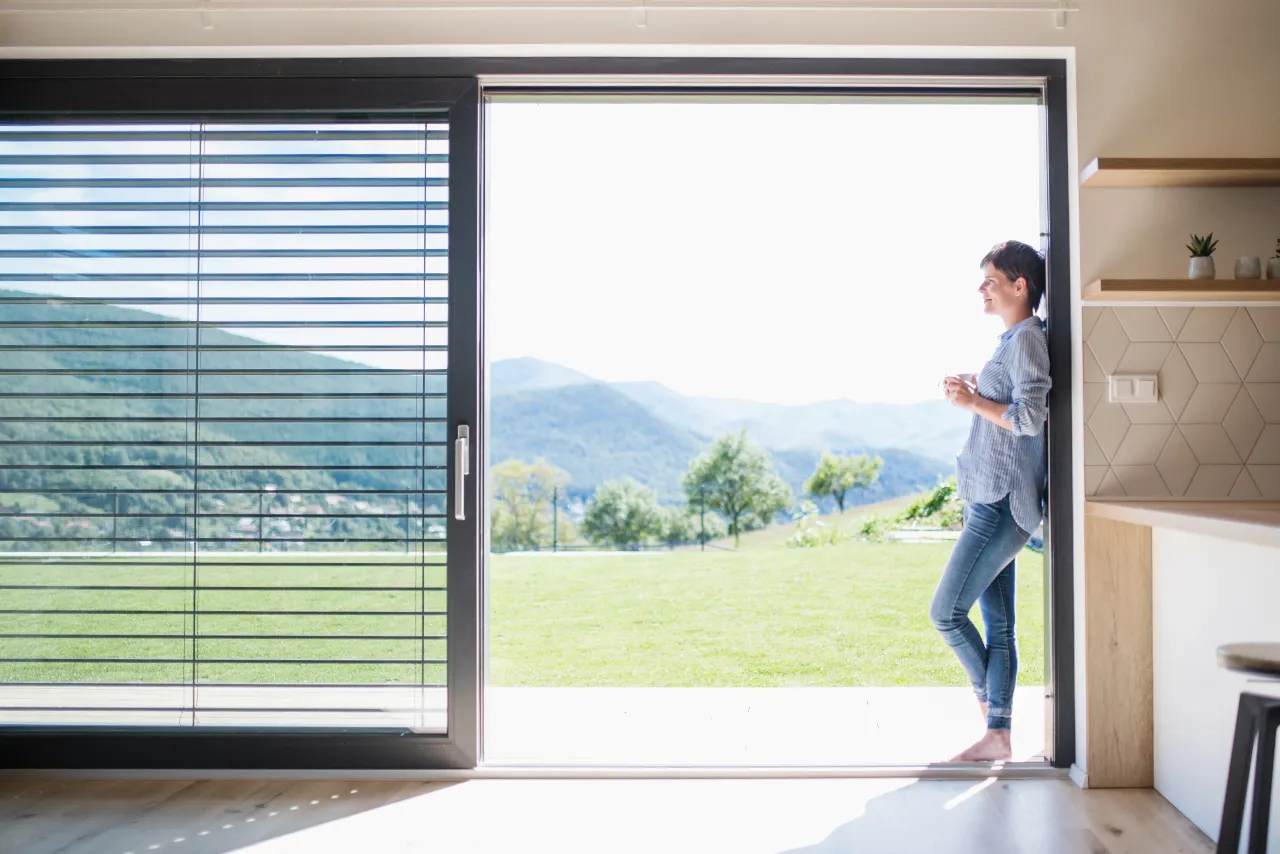 osoba myjąca duże, czyste okno w słonecznym salonie