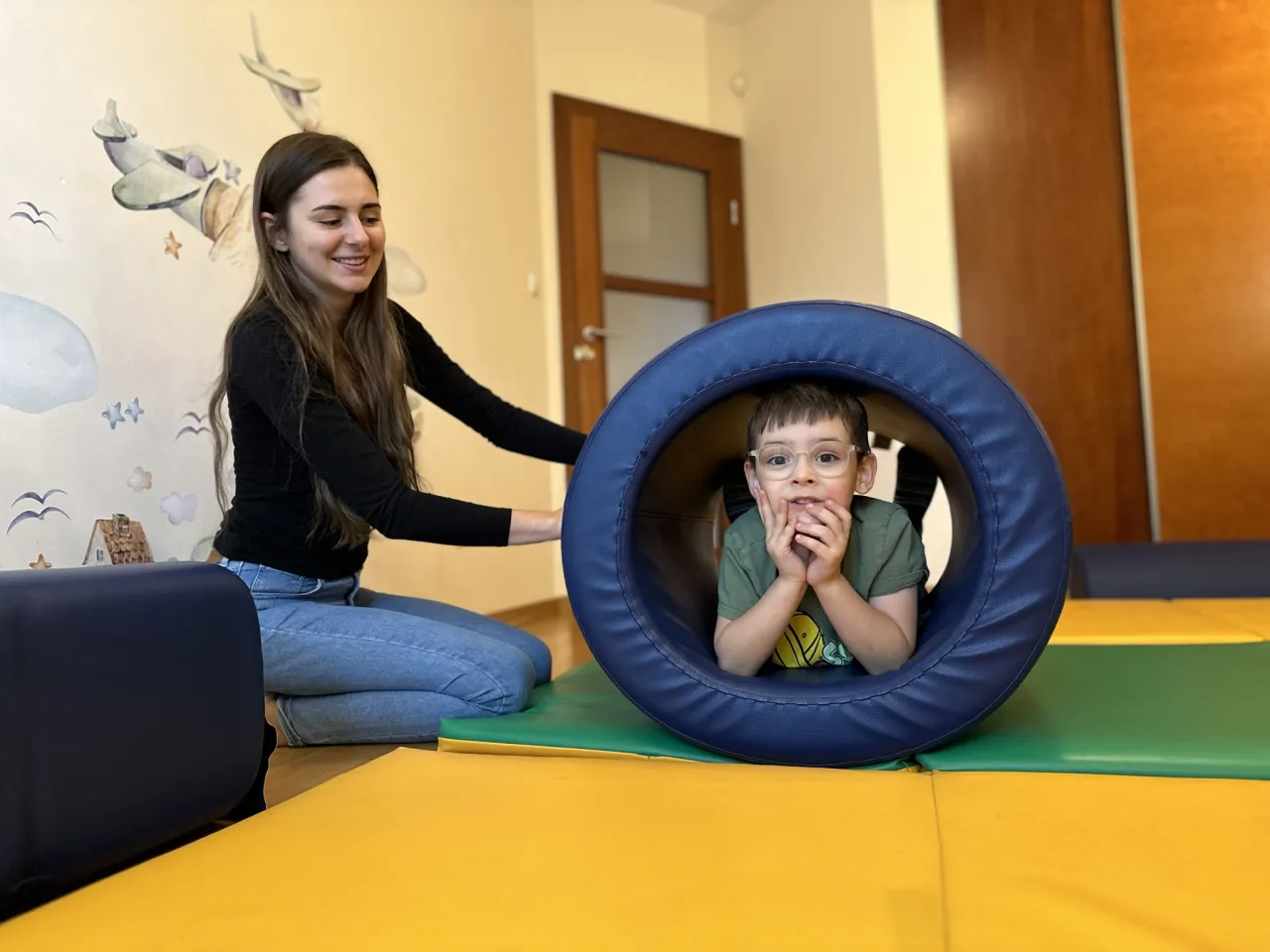 Dziecko na huśtawce sensorycznej z terapeutą