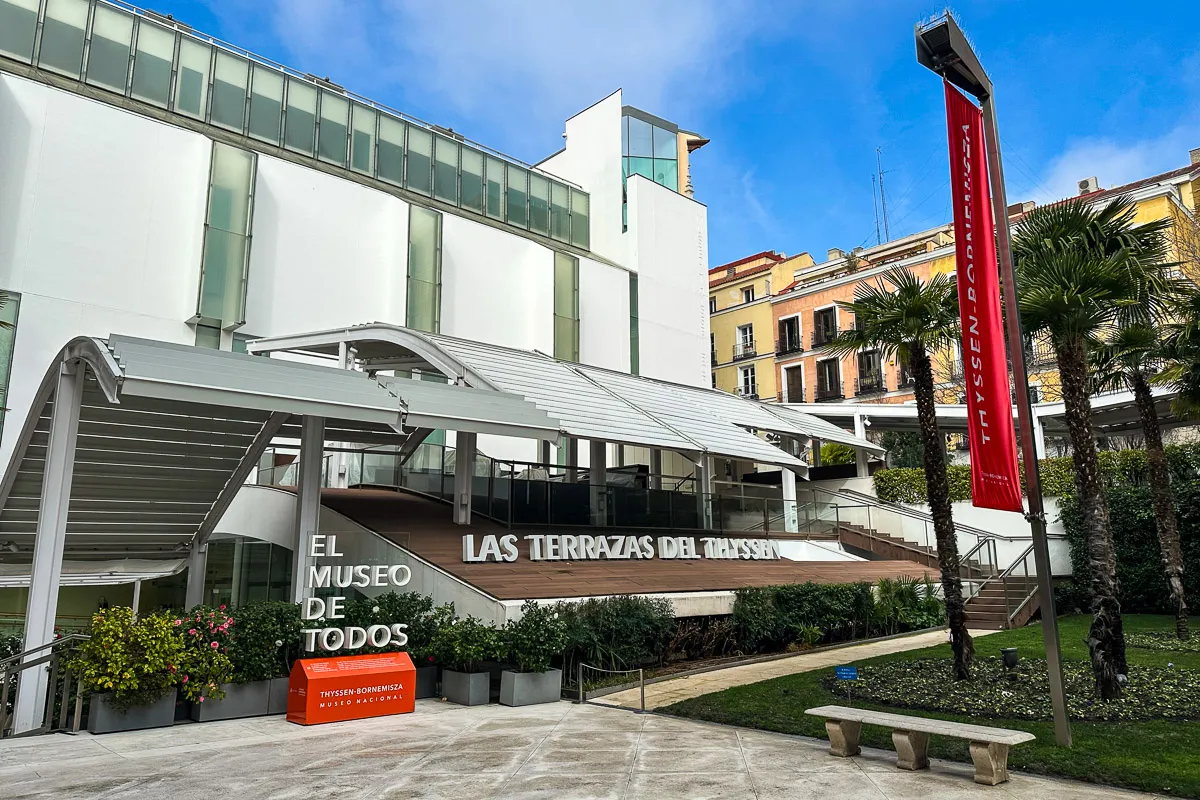 Nowoczesny budynek muzeum sztuki w Madrycie, z palmami i czerwoną flagą z napisem 