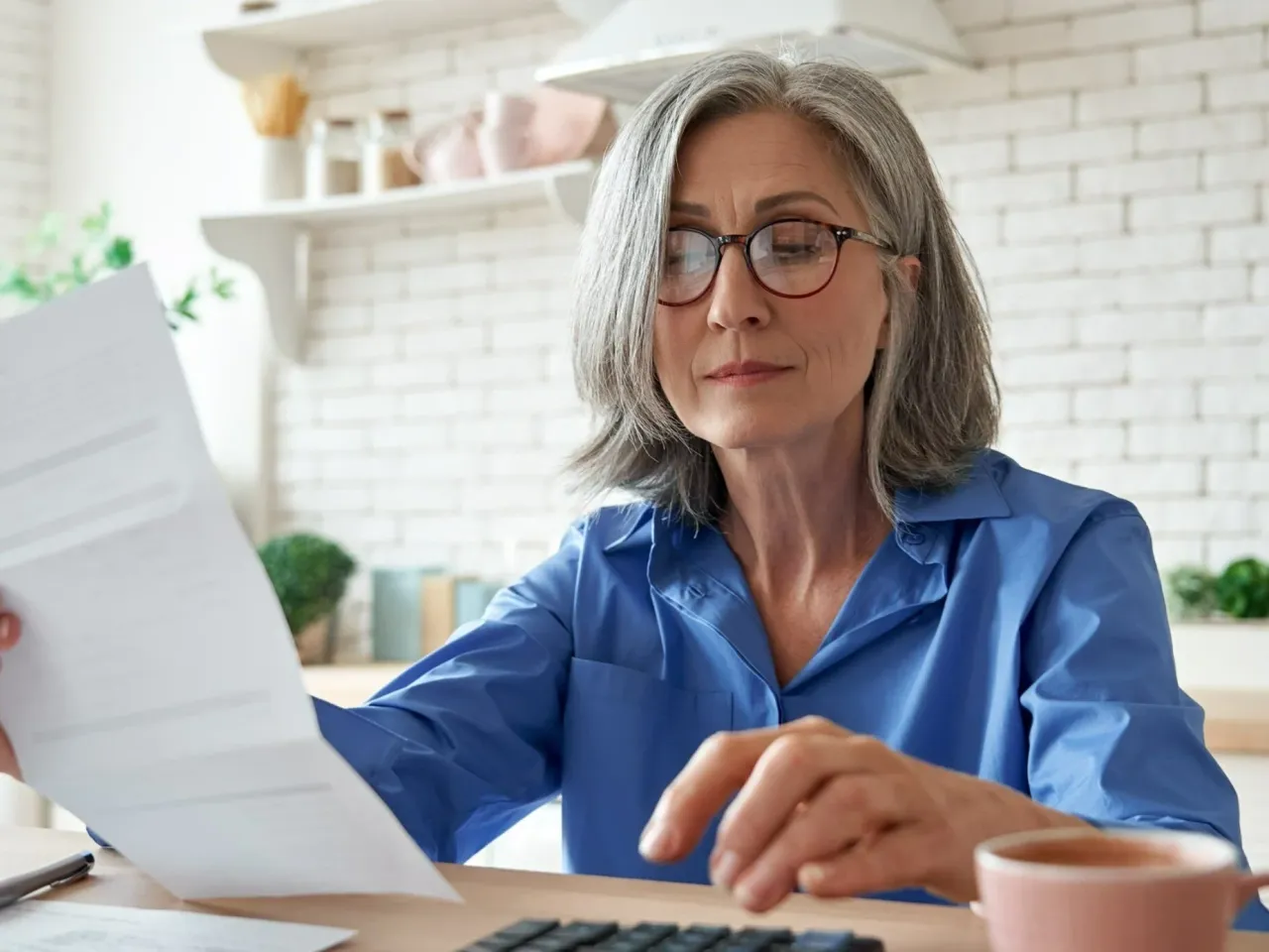 Kobieta w okularach analizuje dokumenty, sprawdzając, komu przysługuje emerytura pomostowa.