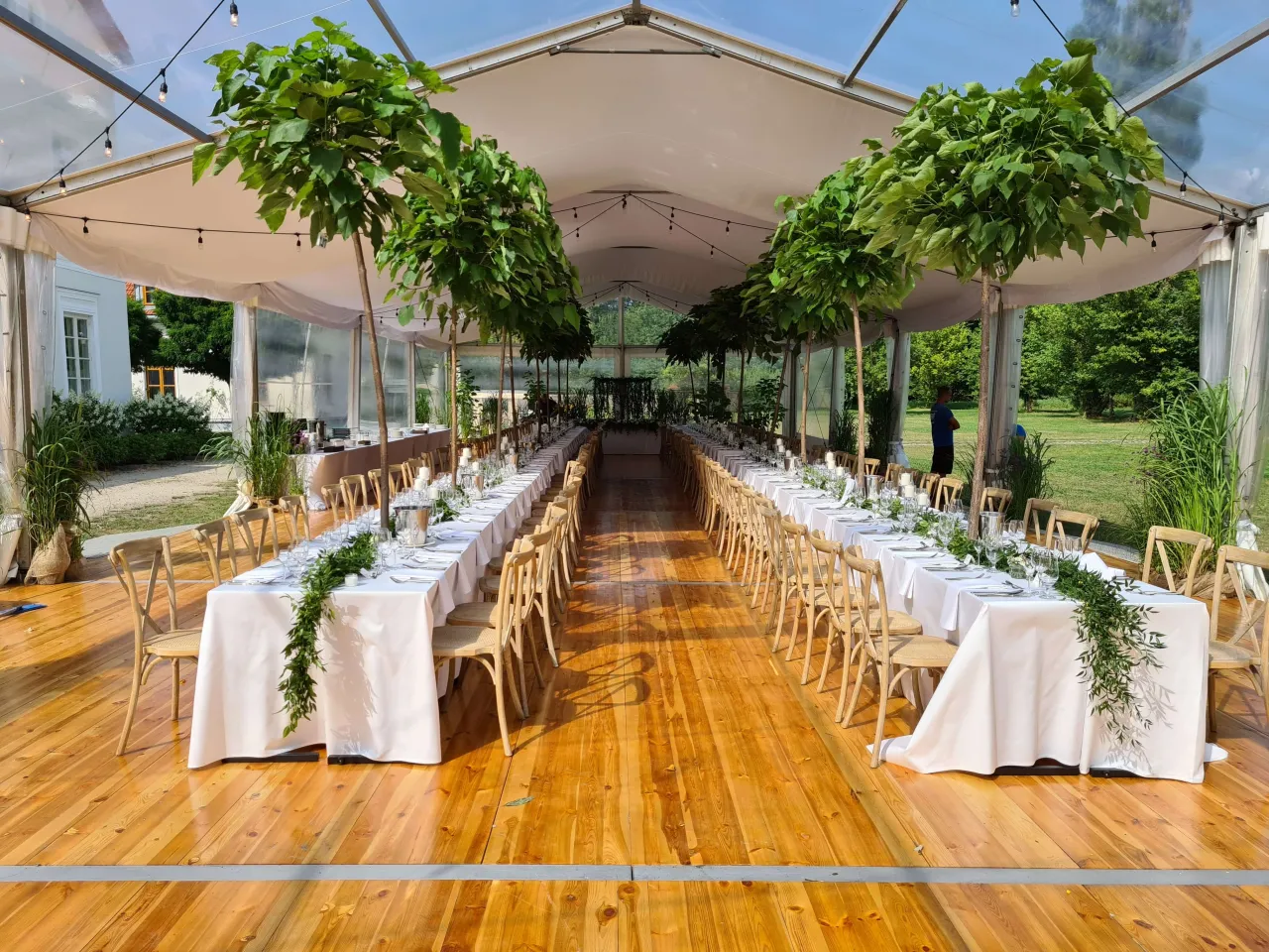 Uroczyste stoły pod namiotem, ozdobione zielenią. Logistyka i plan B dla ślubu w plenerze vs. wesele w stodole.