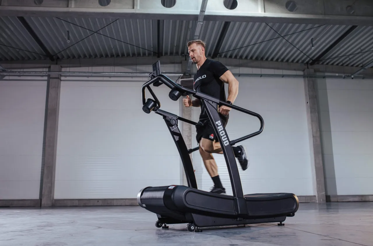 Mężczyzna biegnie na bieżni, zastanawiając się, czy robic cardio na masie. Intensywny trening w nowoczesnej hali.