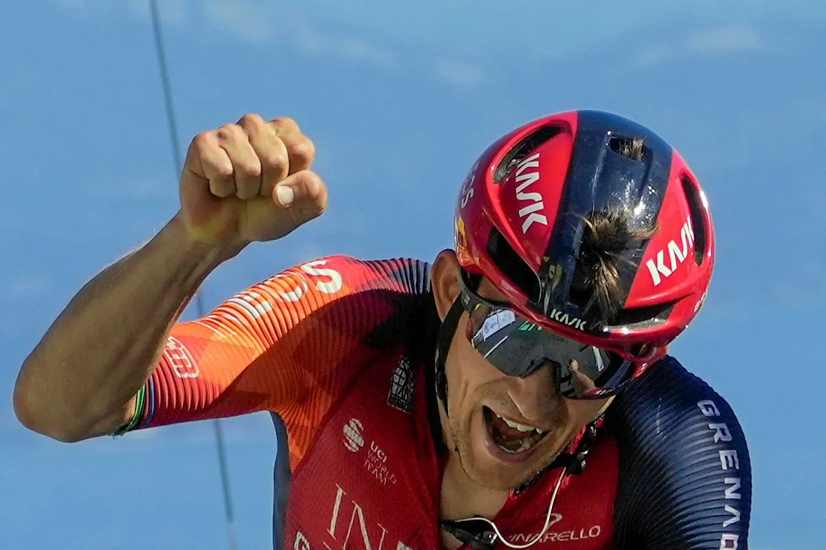 Michał Kwiatkowski, kolarz, triumfuje, unosząc pięść w geście zwycięstwa.