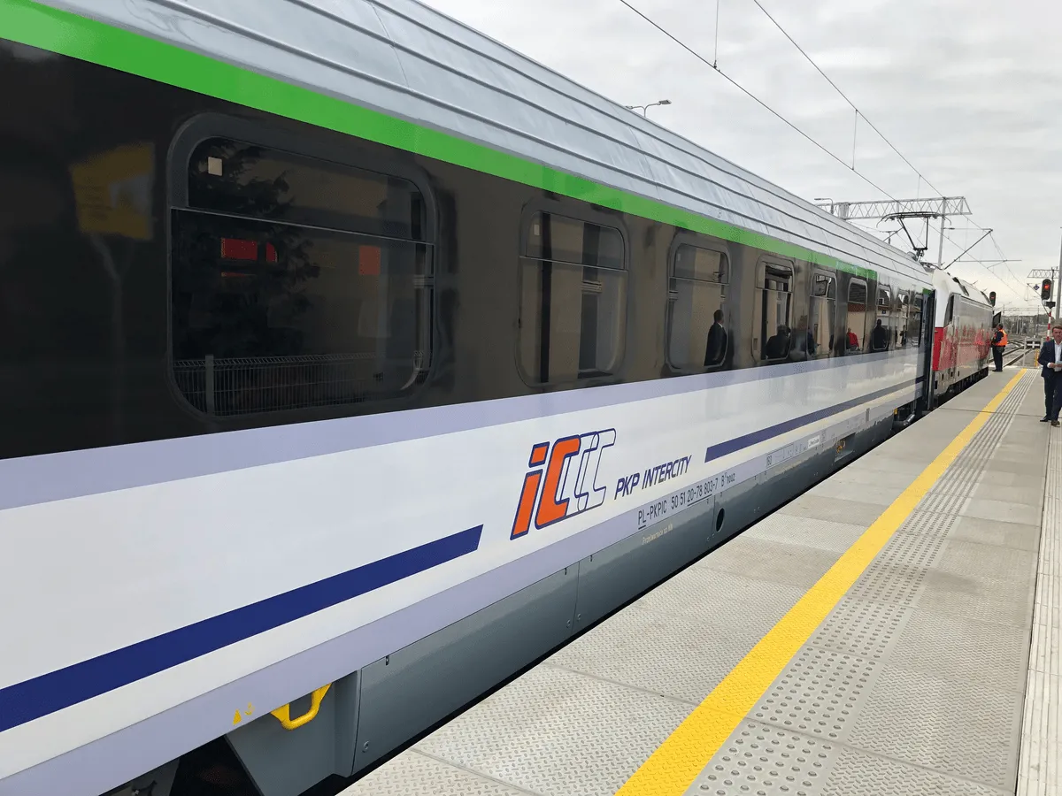PKP Intercity - eic co to za pociąg? Nowoczesny skład z zielonym pasem na tle szarego nieba, gotowy do podróży.