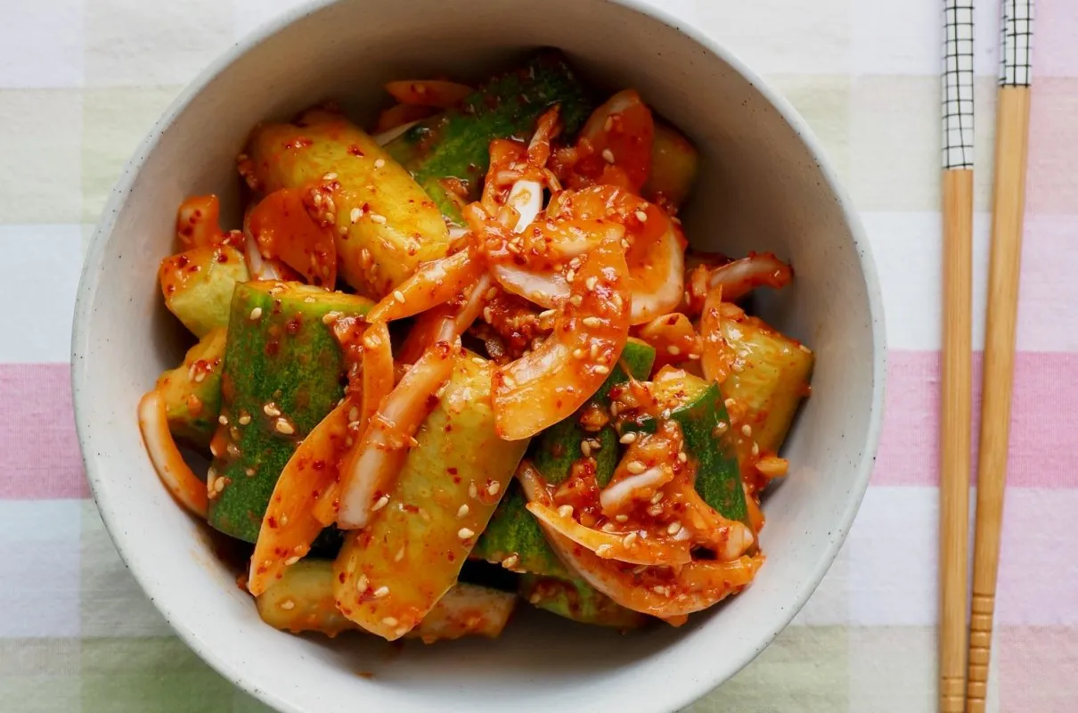 Miseczka pełna pikantnych og&oacute;rk&oacute;w po tajsku, posypanych sezamem. Obok leżą pałeczki.