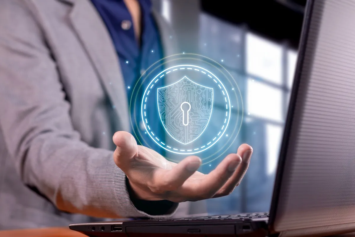 Ochrona danych i aktualizacja systemu. Dłoń trzyma wirtualną tarczę z kluczem, symbolizującą bezpieczeństwo cyfrowe.