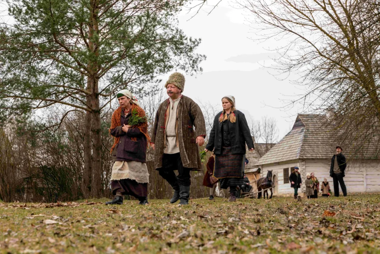 Trzy osoby w strojach ludowych idą przez wieś. Czy to rodzina, która pokazuje, ile pawlak miał dzieci?