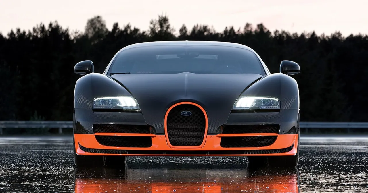 Czarny Bugatti Veyron z pomarańczowymi akcentami, gotowy do przyspieszenia do 100 km/h na mokrej nawierzchni.