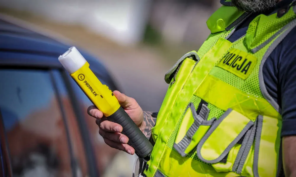 Policjant z alkomatem w drzwiach domu