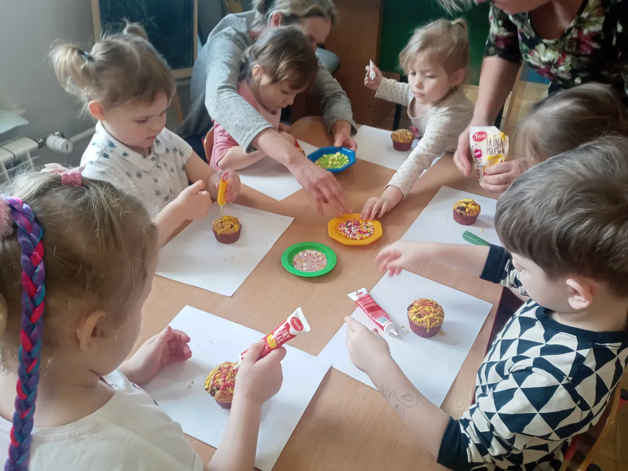 dzieci dekorujące babeczki