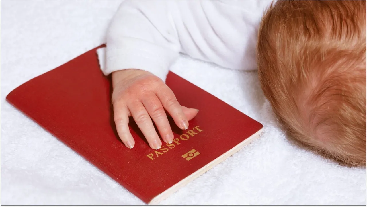 Dziecko z dłonią na czerwonym paszporcie. Czy do Hiszpanii potrzebny jest paszport? Tak, nawet dla niemowlaka.