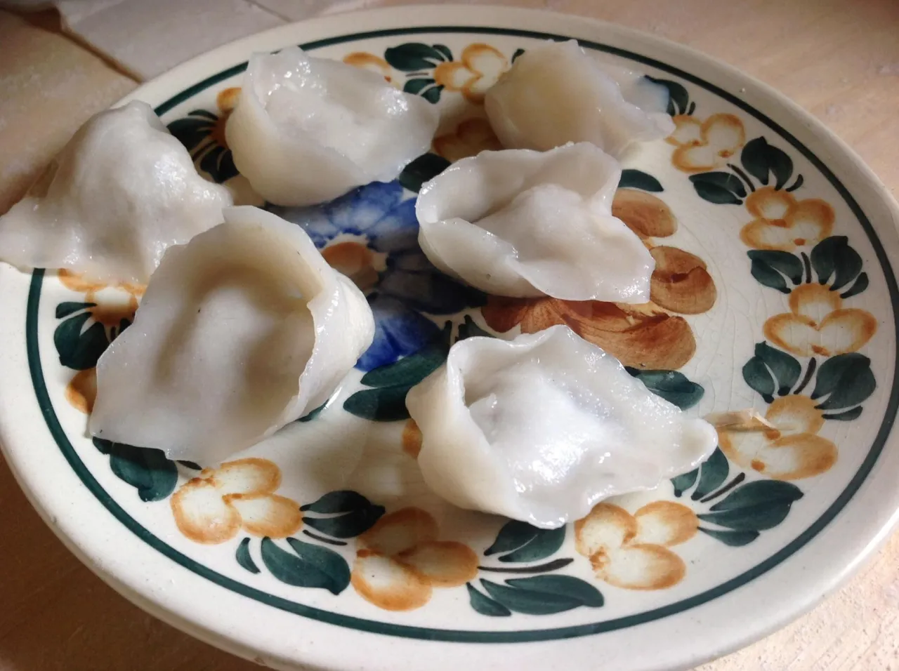 Uszka bezglutenowe przepis: pyszne, białe pierożki na talerzu z kwiatowym wzorem.