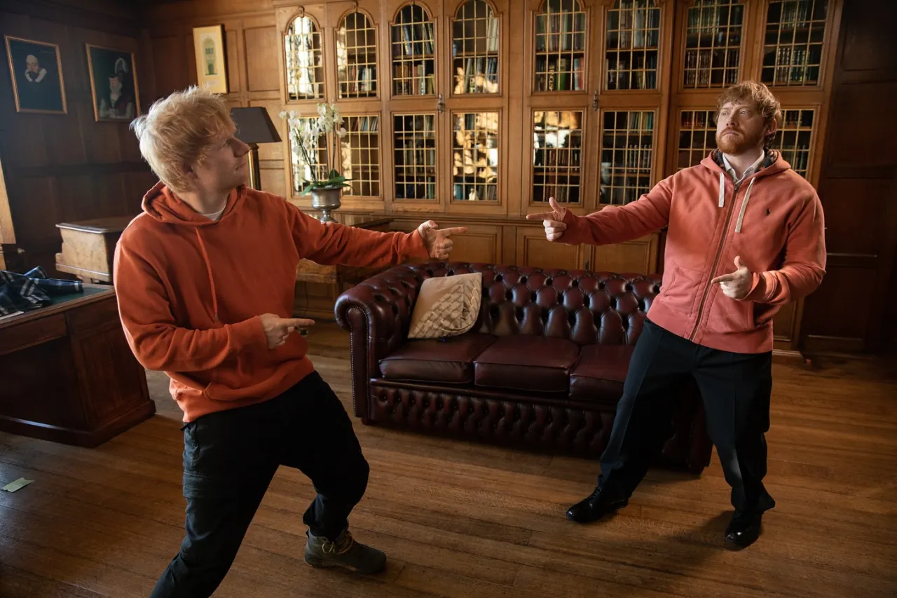 Dwóch Edów Sheeranów w pomarańczowych bluzach, jakby zastanawiali się, czy Ed Sheeran grał w Harrym Potterze.