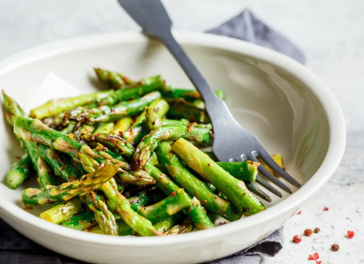 Zielone szparagi w misce, gotowe do podania. Prosty sposób, jak przygotować szparagi na obiad. Widelec czeka na pierwszy kęs.