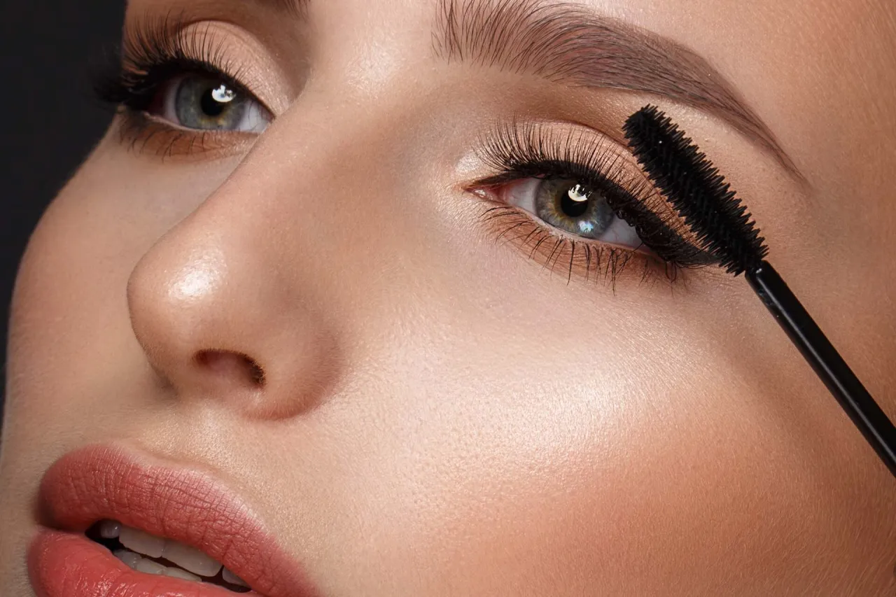 kobieta malująca rzęsy zalotką i tuszem