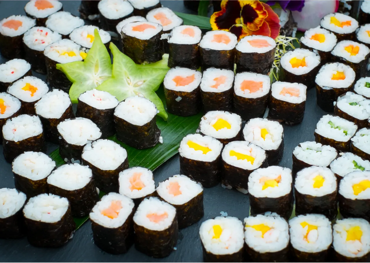 Mn&oacute;stwo sushi maki z łososiem, mango i krewetkami. Piękne, zielone gwiazdki i kwiaty dodają uroku temu japońskiemu sosowi.