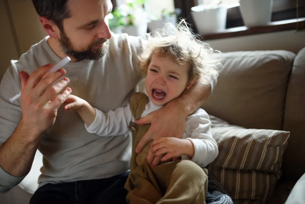 rodzic uspokaja dziecko po podaniu leku